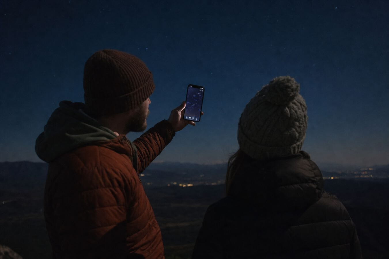 Two people using a smartphone star finder app under a clear night sky